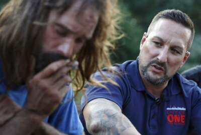 In this Friday, Aug. 10, 2018 photo, Jamie Casey, right, speaks with Brian Peets at a homeless camp in New Bedford, Mass., on Friday, Aug. 10, 2018. “For 20 years I fought and fought and fought against myself. Because you’re your biggest enemy. You know that, right?” Casey told Peets. (AP Photo/Michael Dwyer)