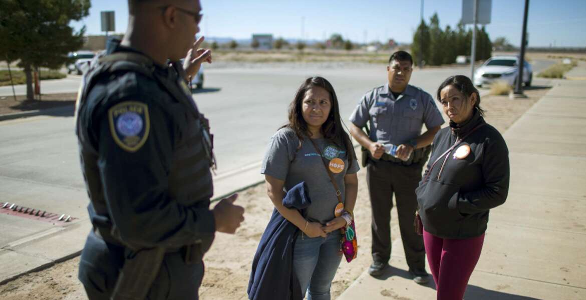 In this Nov. 15, 2018 photo provided by Ivan Pierre Aguirre, Dalila Reynoso-Gonzalez, center left, a program director for the Methodist immigration advocacy group Justice for our Neighbors of East Texas, and another protestor talk with a Department of Homeland Security official outside the Tornillo detention camp holding more than 2,300 migrant teens in Tornillo, Texas. The Trump administration announced in June 2018 that it would open the temporary shelter for up to 360 migrant children in this isolated corner of the Texas desert. Less than six months later, the facility has expanded into a detention camp holding thousands of teenagers - and it shows every sign of becoming more permanent. (Ivan Pierre Aguirre via AP)