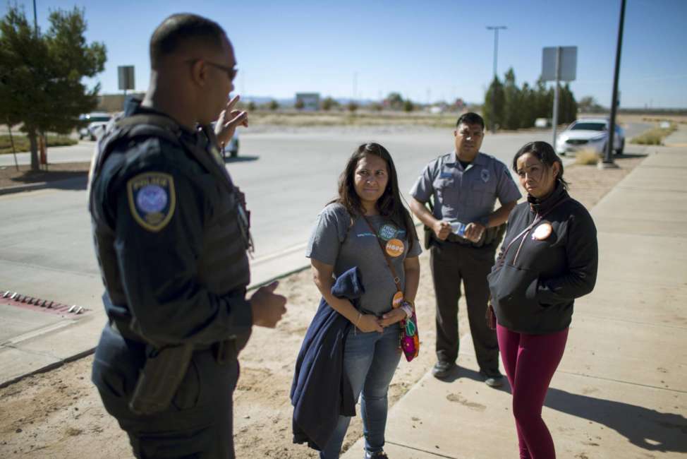 In this Nov. 15, 2018 photo provided by Ivan Pierre Aguirre, Dalila Reynoso-Gonzalez, center left, a program director for the Methodist immigration advocacy group Justice for our Neighbors of East Texas, and another protestor talk with a Department of Homeland Security official outside the Tornillo detention camp holding more than 2,300 migrant teens in Tornillo, Texas. The Trump administration announced in June 2018 that it would open the temporary shelter for up to 360 migrant children in this isolated corner of the Texas desert. Less than six months later, the facility has expanded into a detention camp holding thousands of teenagers - and it shows every sign of becoming more permanent. (Ivan Pierre Aguirre via AP)