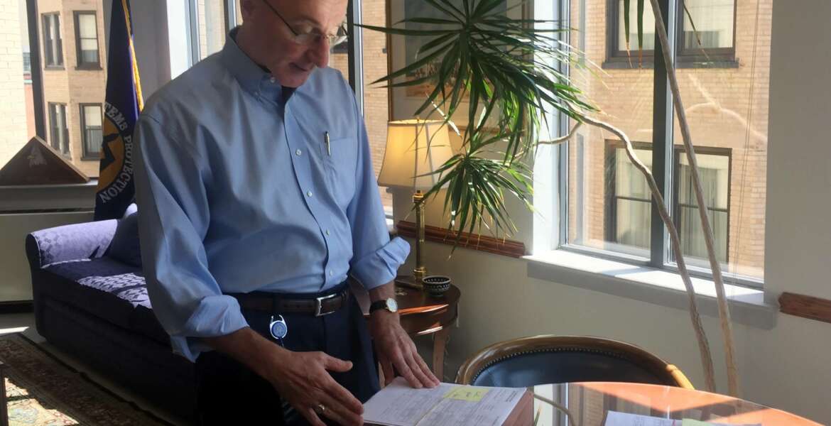 In this Aug. 7, 2018, photo, Mark Robbins, the last remaining member of the Merit Systems Protection Board, looks through stacks of legal cases piled up on his desk in Washington office. Robbins reads through federal workplace disputes, analyzes the cases, marks them with notes and logs his legal opinions. He then passes them along to nobody. He’s the only member of a three-member board that legally can’t operate until the president and Congress give him at least one colleague. (AP Photo/Juliet Linderman)