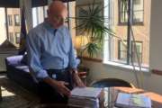 In this Aug. 7, 2018, photo, Mark Robbins, the last remaining member of the Merit Systems Protection Board, looks through stacks of legal cases piled up on his desk in Washington office. Robbins reads through federal workplace disputes, analyzes the cases, marks them with notes and logs his legal opinions. He then passes them along to nobody. He’s the only member of a three-member board that legally can’t operate until the president and Congress give him at least one colleague. (AP Photo/Juliet Linderman)