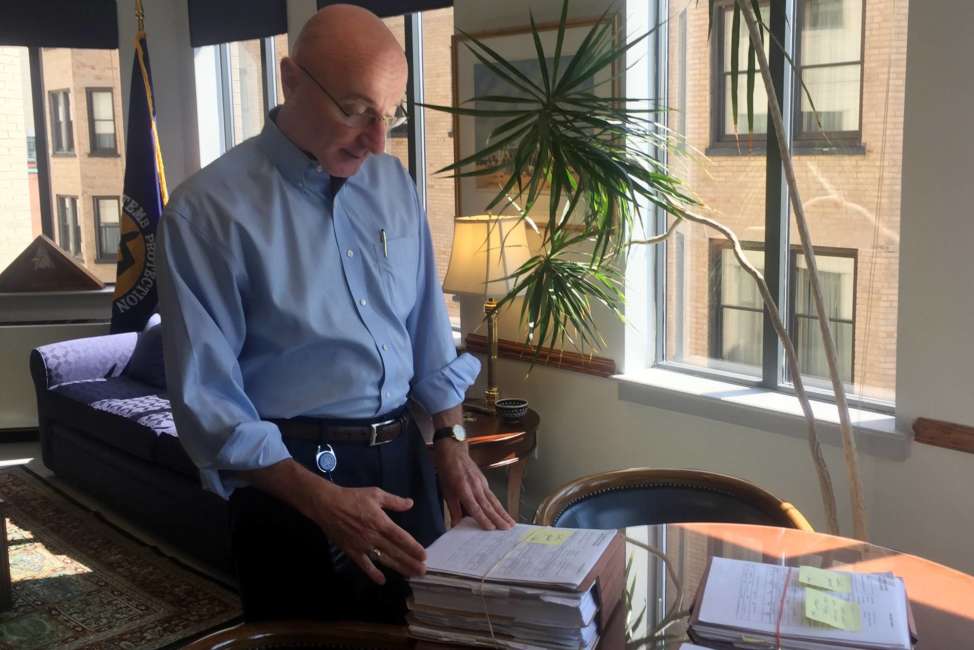 In this Aug. 7, 2018, photo, Mark Robbins, the last remaining member of the Merit Systems Protection Board, looks through stacks of legal cases piled up on his desk in Washington office. Robbins reads through federal workplace disputes, analyzes the cases, marks them with notes and logs his legal opinions. He then passes them along to nobody. He’s the only member of a three-member board that legally can’t operate until the president and Congress give him at least one colleague. (AP Photo/Juliet Linderman)