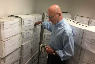In this Aug. 7, 2018, photo, Mark Robbins, the sole member of the Merit Systems Protection Board, walks through the supply closet, pointing to boxes full of cases, in his office in Washington. Robbins reads through federal workplace disputes, analyzes the cases, marks them with notes and logs his legal opinions. He then passes them along to nobody. He’s the only member of a three-member board that legally can’t operate until the president and Congress give him at least one colleague.  (AP Photo/Juliet Linderman)