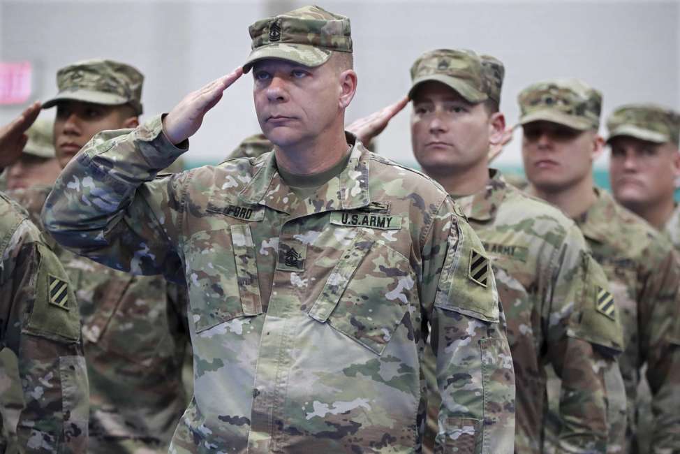 First sergeant Archer Ford, from left, sergeant first class Andreson Neal, and members of the Georgia National Guard's 48th Brigade Combat Team salute the colors during the Casing of Color and Departure Ceremony for their deployment to Afghanistan on Friday, Dec 21, 2018, at Fort Stewart. (Curtis Compton/Atlanta Journal-Constitution via AP)