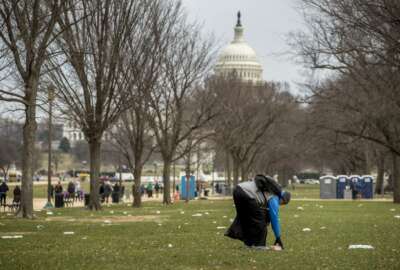 The Capitol building is visible as a man who declined to give his name picks up garbage during a partial government shutdown on the National Mall in Washington, Tuesday, Dec. 25, 2018. (AP Photo/Andrew Harnik)