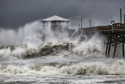 FILE - In this Sept. 13, 2018, file photo, waves slam the Oceana Pier & Pier House Restaurant in Atlantic Beach, N.C. as Hurricane Florence approaches the area.  U.S. Marine Corps leaders say it will cost around $3.6 billion to repair the extensive damage to Camp Lejeune in North Carolina from Hurricane Florence. (Travis Long/The News & Observer via AP, File)