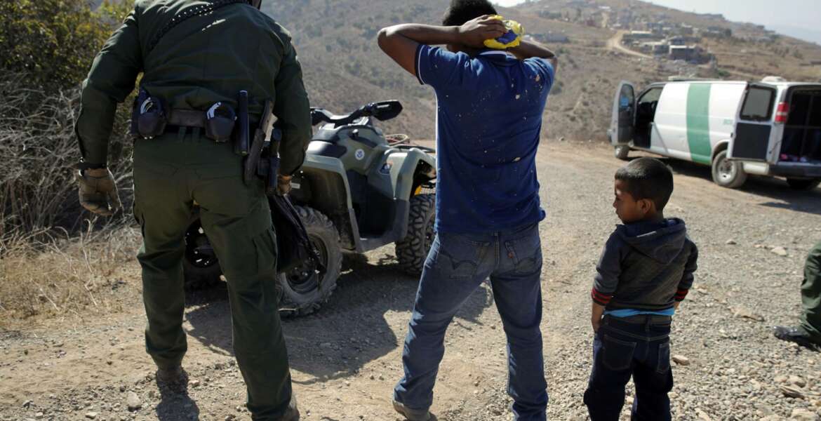 FILE - In this June 28, 2018, file photo, a Guatemalan father and son, who crossed the U.S.-Mexico border illegally, are apprehended by a U.S. Border Patrol agent in San Diego. Children torn from their parents, refugees turned away, tear gas fired on asylum-seekers, and a swath of the globe derided by the president in crude language. In a breathless 2018, they were just a handful of headlines on immigration, one of the year’s most dominant issues. (AP Photo/Jae C. Hong, File)