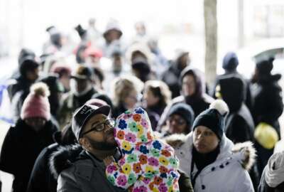 Anthony Spencer, whose wife, Chastity, right, is a furloughed federal worker, holds his daughter, Sydney, as they wait in line with others who are affected by the partial government shutdown for Philabundance volunteers to distribute food under Interstate 95 in Philadelphia, Wednesday, Jan. 23, 2019. (AP Photo/Matt Rourke)