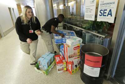 Port of Seattle workers Danica Doyle, left, and Matondo Wawa, right, collect items donated to federal workers affected by the government shutdown at Seattle-Tacoma International Airport, Friday, Jan. 25, 2019 in Seattle. The workers said the Port would continue to accept donations despite a short-term deal to reopen the government for three weeks announced Friday by President Donald Trump. (AP Photo/Ted S. Warren)