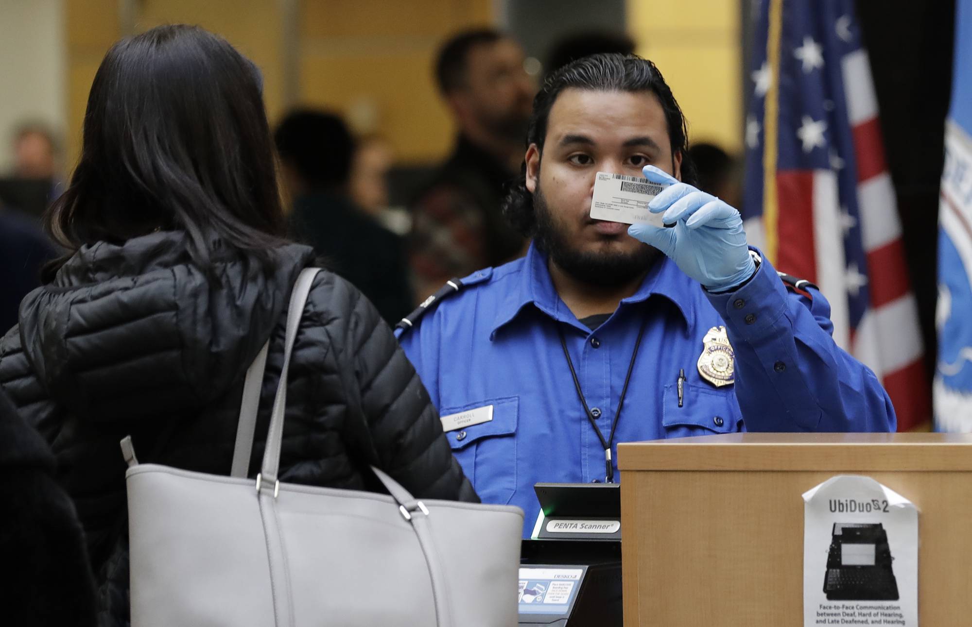 A TSA worker checks an identification card, Friday, Jan. 25, 2019, at Seattle-Tacoma International Airport in Seattle. Yielding to mounting pressure and growing disruption, President Donald Trump and congressional leaders on Friday reached a short-term deal to reopen the government for three weeks while negotiations continue over the president's demands for money to build his long-promised wall at the U.S.-Mexico border. (AP Photo/Ted S. Warren)