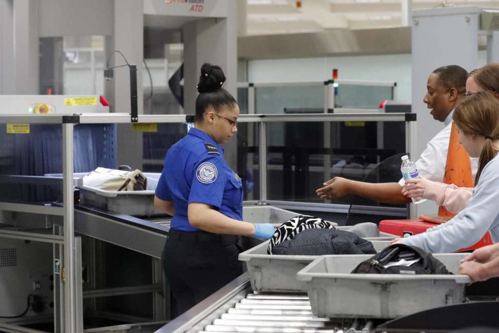 A Transportation Security Administration employee helps air travelers submit their bags for inspection at Hartsfield Jackson Atlanta International Airport Monday, Jan. 7, 2019, in Atlanta. (AP Photo/John Bazemore)