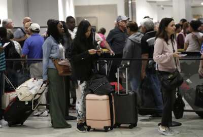 FILE- In this Jan. 18, 2019, file photo passengers wait in line at a security checkpoint at Miami International Airport in Miami. While security screeners and air traffic controllers have been told to keep working, Federal Aviation Administration safety inspectors weren’t, until the agency began recalling some Jan. 12. About 2,200 of the more than 3,000 inspectors are now back on the job, overseeing work done by airlines, aircraft manufacturers and repair shops. The government says they’re doing critical work but forgoing such tasks as issuing new pilot certificates.(AP Photo/Lynne Sladky, File)