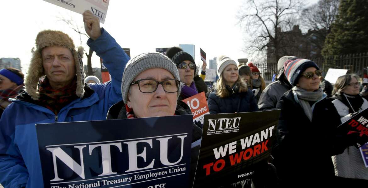United States Department of Agriculture employee Lori Lodato, of Wilmington, Mass., display placards during a rally by federal employees and supporters, Thursday, Jan. 17, 2019, in front of the Statehouse in Boston, held to call for an end of the partial shutdown of the federal government. (AP Photo/Steven Senne)