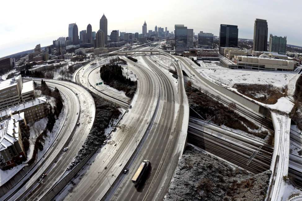 FILE - In this Jan. 29, 2014 file photo, taken with a fisheye lens looking south toward downtown Atlanta, the ice-covered interstate system shows the remnants of a winter snow storm, in Atlanta. The National Weather Service projects that up to an inch (2.5 centimeters) of snow is possible Tuesday in Atlanta, with up to 2 inches (5 centimeters) in far northern suburbs. Forecasters warn of the possibility of ice-glazed roads and highways. (AP Photo/David Tulis, File)