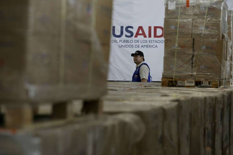 A man walks past boxes of USAID humanitarian aid