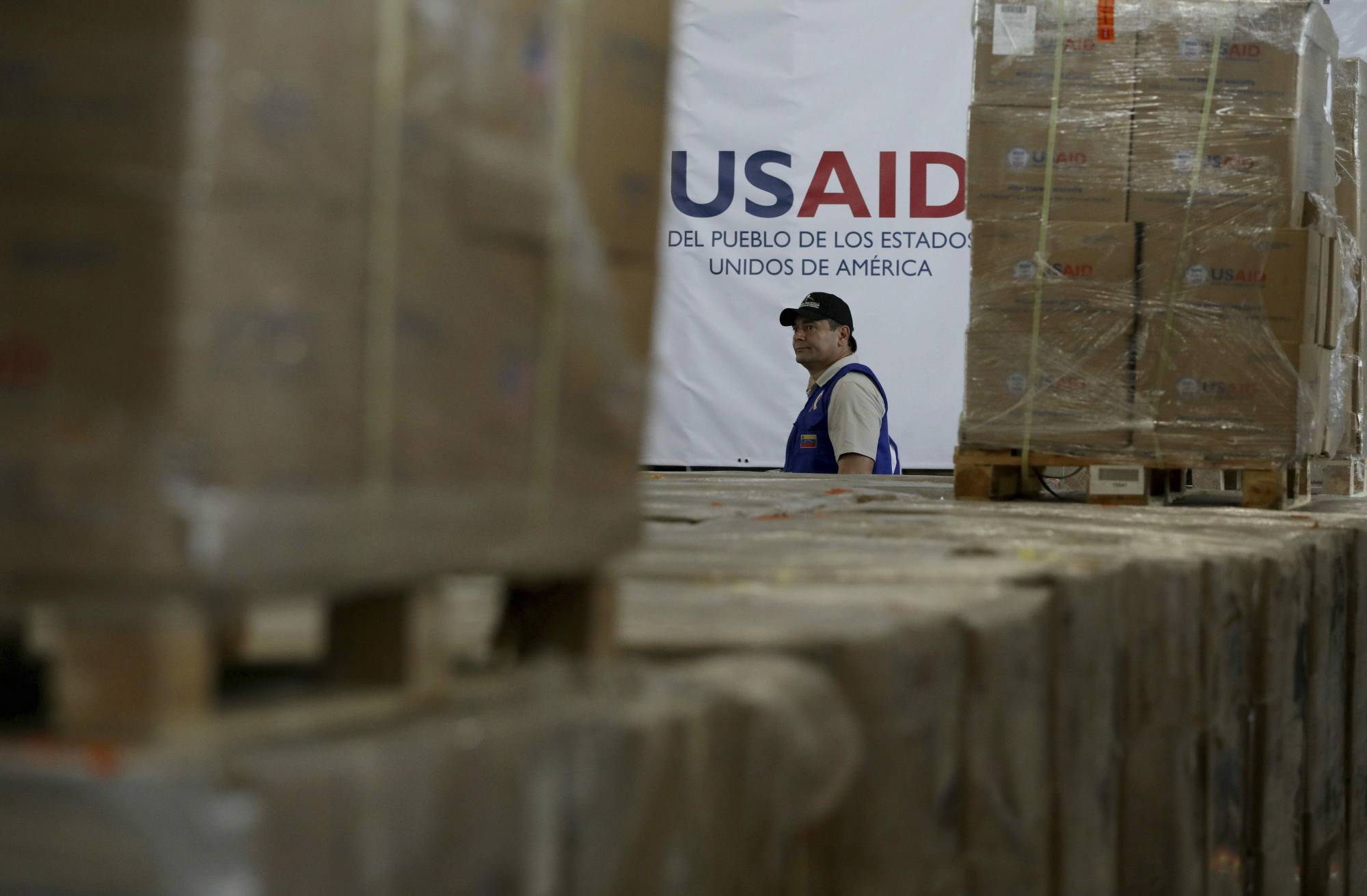 A man walks past boxes of USAID humanitarian aid at a warehouse at the Tienditas International Brigde on the outskirts of Cucuta, Colombia, Thursday, Feb. 21, 2019, on the border with Venezuela. Venezuela's President Nicolas Maduro said he’s weighing whether to shut down the border with Colombia, where the bulk of aid meant for Venezuela is being stockpiled and exiled leaders have been gathering ahead of a fundraising concert Friday. (AP Photo/Fernando Vergara)