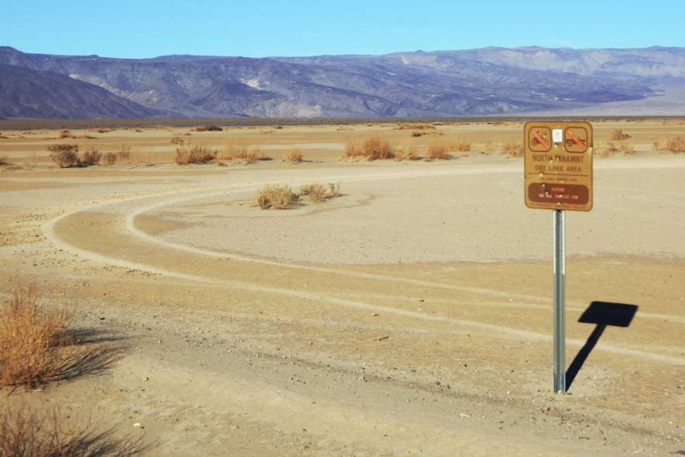 This undated photo provided by the U.S. National Park Service shows vehicle tracks beyond a sign banning vehicles in the North Panamint dry lake area during the recent federal government shutdown in an area of Death Valley National Park, Calif. National parks across the United States are scrambling to clean up and repair damage caused by visitors and storms during the government shutdown while bracing for another possible closure ahead of the usually busy President's Day weekend. (National Park Service via AP)