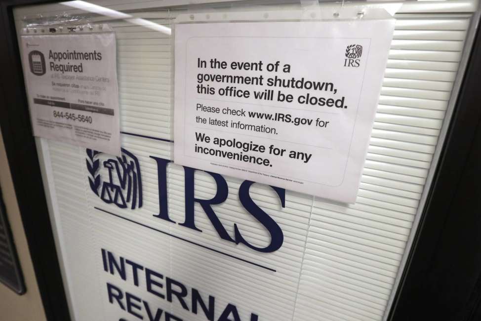 FILE- In this Jan. 16, 2019, file photo doors at the Internal Revenue Service (IRS) in the Henry M. Jackson Federal Building are locked and covered with blinds as a sign posted advises that the office will be closed during the partial government shutdown in Seattle. Disruptions from last month’s partial government shutdown caused a “shocking” deterioration in the IRS’ telephone help for taxpayers in the first week of the filing season, the agency’s watchdog said in a report released Tuesday, Feb. 12. (AP Photo/Elaine Thompson, File)