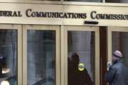 FILE - In this Thursday, Dec. 14, 2017, file photo, a person with a smartphone enters the Federal Communications Commission building in Washington. Tech companies and nearly two dozen U.S. states clashed with the government in federal court Friday, Feb. 1, 2019, over the repeal of net neutrality, a set of Obama-era rules aimed at preventing big internet providers from discriminating against certain technology and services. The action rolling back the neutrality rules "is a stab in the heart of the Communications Act," said attorney Pantelis Michalopoulos, referring to the Depression-era law that established the FCC. (AP Photo/Carolyn Kaster, File)