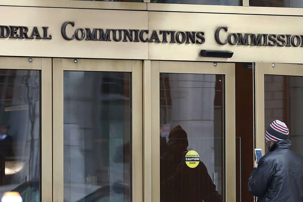 FILE - In this Thursday, Dec. 14, 2017, file photo, a person with a smartphone enters the Federal Communications Commission building in Washington. Tech companies and nearly two dozen U.S. states clashed with the government in federal court Friday, Feb. 1, 2019, over the repeal of net neutrality, a set of Obama-era rules aimed at preventing big internet providers from discriminating against certain technology and services. The action rolling back the neutrality rules "is a stab in the heart of the Communications Act," said attorney Pantelis Michalopoulos, referring to the Depression-era law that established the FCC. (AP Photo/Carolyn Kaster, File)