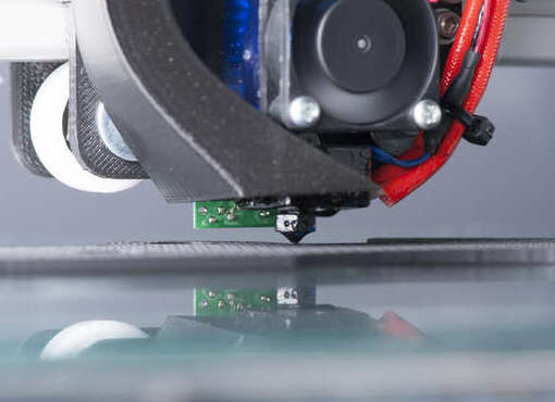 Photo of a 3D printer actually in action printing a part. You can see the fan moving and the part it is printing.