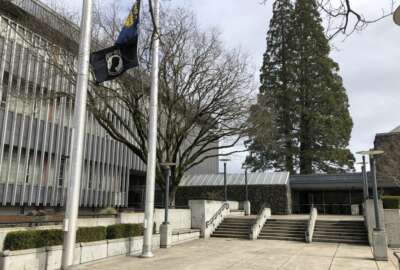 In this photo taken March 7, 2019, flags, including a POW/MIA flag, flap in a breeze in front of the Lane County Circuit Court building where the Veterans Treatment Court is held in Eugene, Ore. Military veterans who are struggling with addiction and have tangled with the law are being given a second chance in an Oregon courtroom. But the Veterans Treatment Court and 40 other specialty courts in Oregon are at risk of losing their federal funding unless the state enforces federal immigration policies. (AP Photo/Andrew Selsky)