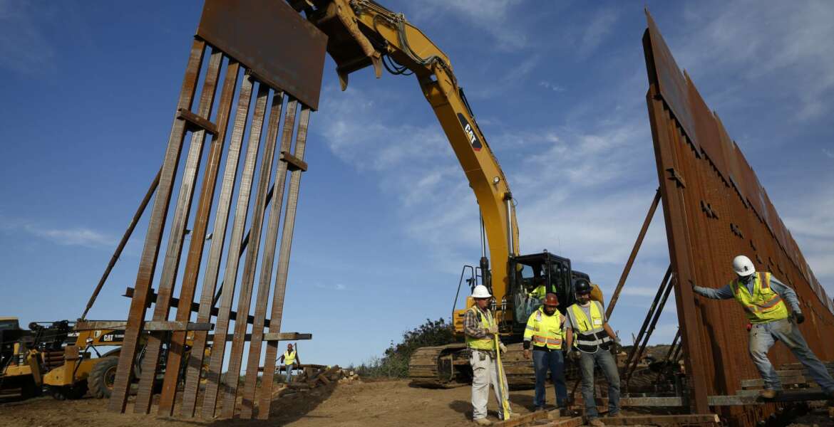 FILE - In this Jan. 9, 2019 file photo, construction crews install new border wall sections seen from Tijuana, Mexico. Sen. Dick Durbin, D-Ill., says the Pentagon is planning to tap $1 billion in leftover funds from military pay and pensions accounts to help President Donald Trump pay for his long-sought border wall. Durbin told The Associated Press, “it’s coming out of military pay and pensions, $1 billion, that’s the plan.”(AP Photo/Gregory Bull, File)