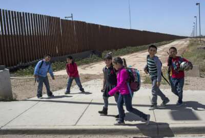 FILE - In this March 31, 2017 file photo, Columbus Elementary School students walk towards the U.S. port of entry on the border with Puerto Palomas, Mexico, after attending school in Columbus, N.M. The Army Corps of Engineers announced Wednesday, April 10, 2019, they have awarded contracts totaling nearly $1 billion for removal and replacement of vehicle fencing with pedestrian fencing along two sections of the U.S.-Mexico border. Fourty-six miles of bollard-style barrier will be installed near Columbus, N.M, and 11 miles of bollard-type barrier will be installed in a Border Patrol sector centered on Yuma, Ariz. (AP Photo/Rodrigo Abd, File)