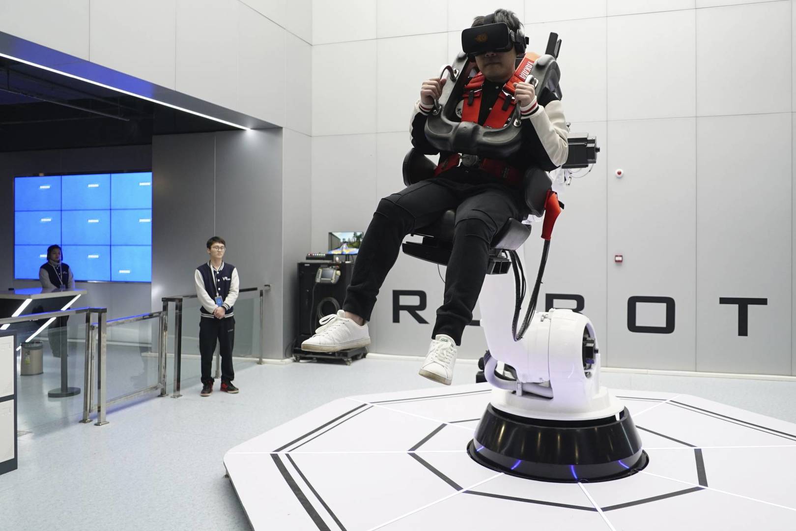 In this April 2, 2019, photo, a visitor rides a virtual roller coaster ride operated by a robotic arm in a VR theme park in Nanchang, China. One of the largest virtual reality theme parks in the world has opened its doors in southwestern China, sporting 42 rides and exhibits from VR bumper cars to VR shoot-em-ups. It's part of an effort by Beijing to get ordinary people excited about the technology - part of a long-term bet that VR will come into widespread use. (AP Photo/Dake Kang)