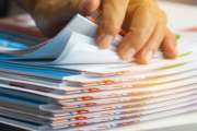 Businessman hands searching unfinished documents stacks of paper files on office desk for report papers, piles of sheet achieves with clips on table, Document is written, drawn,presented.