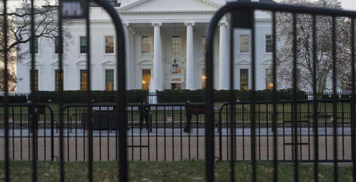 In this March 24, 2019 photo, The White House is seen behind security barriers in Washington. A White House official turned whistleblower says dozens of people in President Donald Trump’s administration were granted access to classified information despite “disqualifying issues” in their backgrounds including concerns about foreign influence, drug use and criminal conduct.  (AP Photo/Cliff Owen)