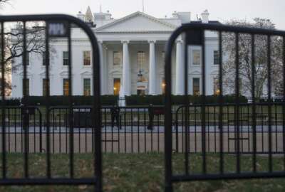 In this March 24, 2019 photo, The White House is seen behind security barriers in Washington. A White House official turned whistleblower says dozens of people in President Donald Trump’s administration were granted access to classified information despite “disqualifying issues” in their backgrounds including concerns about foreign influence, drug use and criminal conduct.  (AP Photo/Cliff Owen)