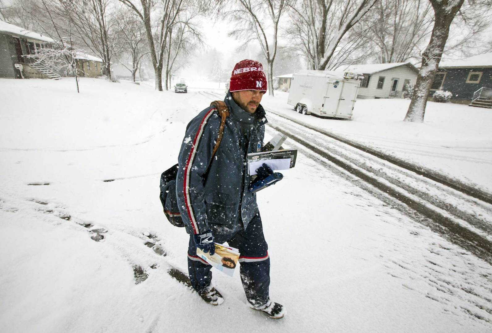 United States Postal Service city carrier Chad Jacobs delivers mail along 16th Avenue Northwest as snow falls, Wednesday, April 10, 2019, in Rochester, Minn. Jacobs said he doesn't mind cold and prefers it over hot days. (Andrew Link/The Rochester Post-Bulletin via AP)