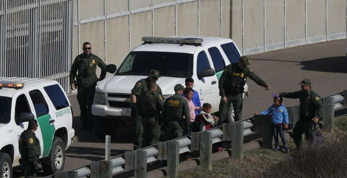 FILE - In this Dec. 9, 2018 file photo, a woman and children are ushered into cars by U.S. Border Patrol agents after crossing illegally over the border wall into San Diego, Calif., as seen from Tijuana, Mexico. A federal judge in California on Friday, May 17, 2019, will consider a challenge to President Donald Trump's plan to tap billions of dollars from the Defense and Treasury departments to build his prized border wall with Mexico. (AP Photo/Rebecca Blackwell, File)