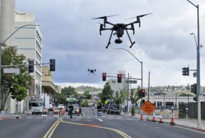 In this May 21, 2019 photo, two drones fly above Lake Street in downtown Reno, Nev., on, as part of a NASA simulation to test emerging technology that someday will be used to manage travel of hundreds of thousands of commercial, unmanned aerial vehicles (UAVs) delivering packages. It marked the first time such tests have been conducted in an urban setting. (AP Photo/Scott Sonner)