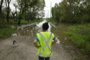 In this photo taken May 8, 2019, Tammy Kilgore as part of her duties with the local volunteer fire department, checks high water covering a road leading to the small community of Mosby, Mo. "The floods, I'm tired of dealing with them, I really am," she said. (AP Photo/Charlie Riedel)