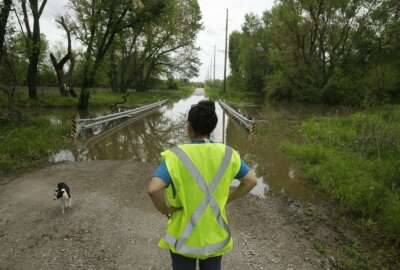 In this photo taken May 8, 2019, Tammy Kilgore as part of her duties with the local volunteer fire department, checks high water covering a road leading to the small community of Mosby, Mo. 