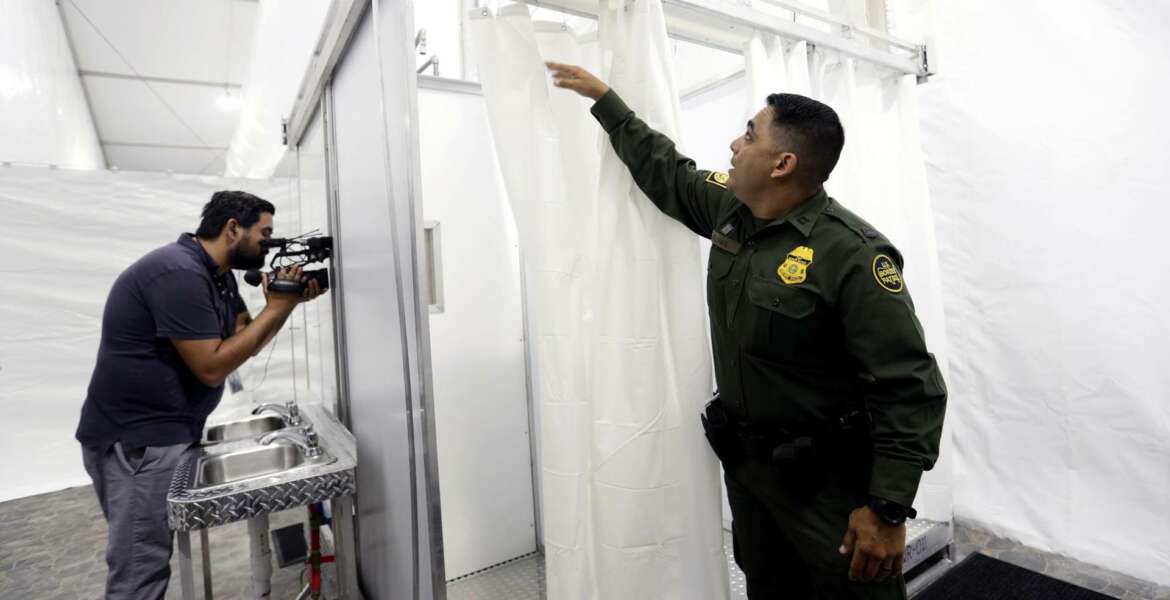 Border Patrol agent E. Flores shows the shower section during a media tour of a new U.S. Customs and Border Protection temporary facility near the Donna International Bridge, Thursday, May 2, 2019, in Donna, Texas. Officials say the site will primarily be used as a temporary site for processing and care of unaccompanied migrant children and families and will increase the Border Patrol's capacity to process migrant families. (AP Photo/Eric Gay)