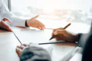 Client signing a real estate contract on desk in office.