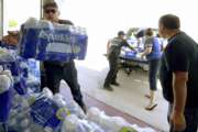 Shawn Dodson, left, with the San Bernardino County Fire Department, stacks cases of water donated by Vince Burns, right, from Ridgecrest, at San Bernardino County Fire Station 57 Saturday, July 6, 2019, in Trona, Calif. The area has been hit with two major earthquakes since Thursday. In Trona, a town of about 2,000 people considered the gateway to Death Valley, fire officials said dozens of structures were damaged. San Bernardino County Supervisor Robert Lovingood said FEMA delivered a tractor-trailer full of bottled water because of damage to water lines. Newsom declared a state of emergency for the county. (Will Lester/The Orange County Register via AP)