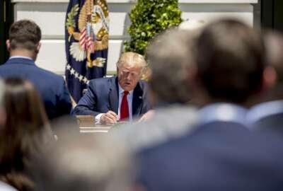 Company representatives invited to the White House, walk towards President Donald Trump as he signs an executive order during a Made in America showcase on the South Lawn White House in Washington, Monday, July 15, 2019. (AP Photo/Andrew Harnik)