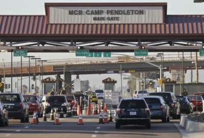 FILE - In this Nov. 13, 2013 file photo vehicles file through the main gate of Camp Pendleton Marine Base at Camp Pendleton, Calif. A human smuggling investigation by the military led to the arrest of 16 Marines Thursday, July 25, 2019 while carrying out a battalion formation at California's Camp Pendleton, a base about an hour's drive from the U.S.-Mexico border. (AP Photo/Lenny Ignelzi, File)