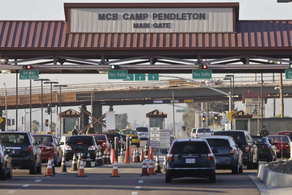 FILE - In this Nov. 13, 2013 file photo vehicles file through the main gate of Camp Pendleton Marine Base at Camp Pendleton, Calif. A human smuggling investigation by the military led to the arrest of 16 Marines Thursday, July 25, 2019 while carrying out a battalion formation at California's Camp Pendleton, a base about an hour's drive from the U.S.-Mexico border. (AP Photo/Lenny Ignelzi, File)