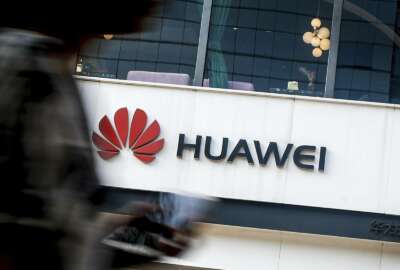 FILE - In this July 30, 2019, file photo a woman walks by a Huawei retail store in Beijing. The U.S. government gave chipmakers and technology companies a 90-day extension to sell products to technology giant Huawei. China has criticized Washington's opposition to Chinese-made next-generation telecoms technology after Vice President Mike Pence called on Iceland and other governments to find alternatives. (AP Photo/Andy Wong, File)