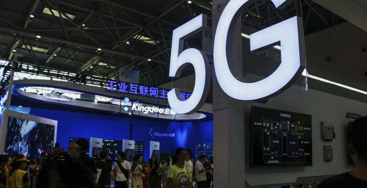 In this Tuesday, Aug. 27, 2019, photo, visitors tour an exhibitor booth with a 5G on display at the Smart China Expo in southwest China's Chongqing Municipality. The World Bank and a Chinese Cabinet agency have urged Beijing to roll back plans for government-led technology development that are fueling a tariff war with Washington. (Chinatopix via AP)