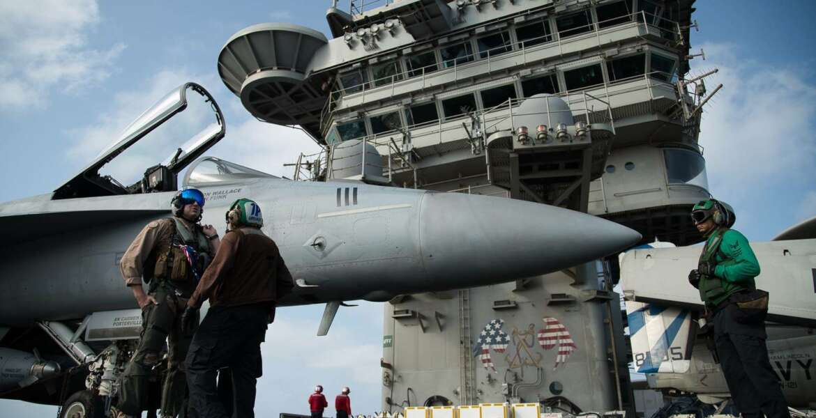 FILE - In this June 3, 2019 file photo, a pilot speaks to a crew member by an F/A-18 fighter jet on the deck of the USS Abraham Lincoln aircraft carrier in the Arabian Sea. The U.S. Navy is trying to put together a new coalition of nations to counter what it sees as a renewed maritime threat from Iran. Meanwhile, Iran finds itself backed into a corner and ready for a possible conflict. It stands poised on Friday, Sept. 6, 2019, to further break the terms of its 2015 nuclear deal with world powers. (AP Photo/Jon Gambrell, File)