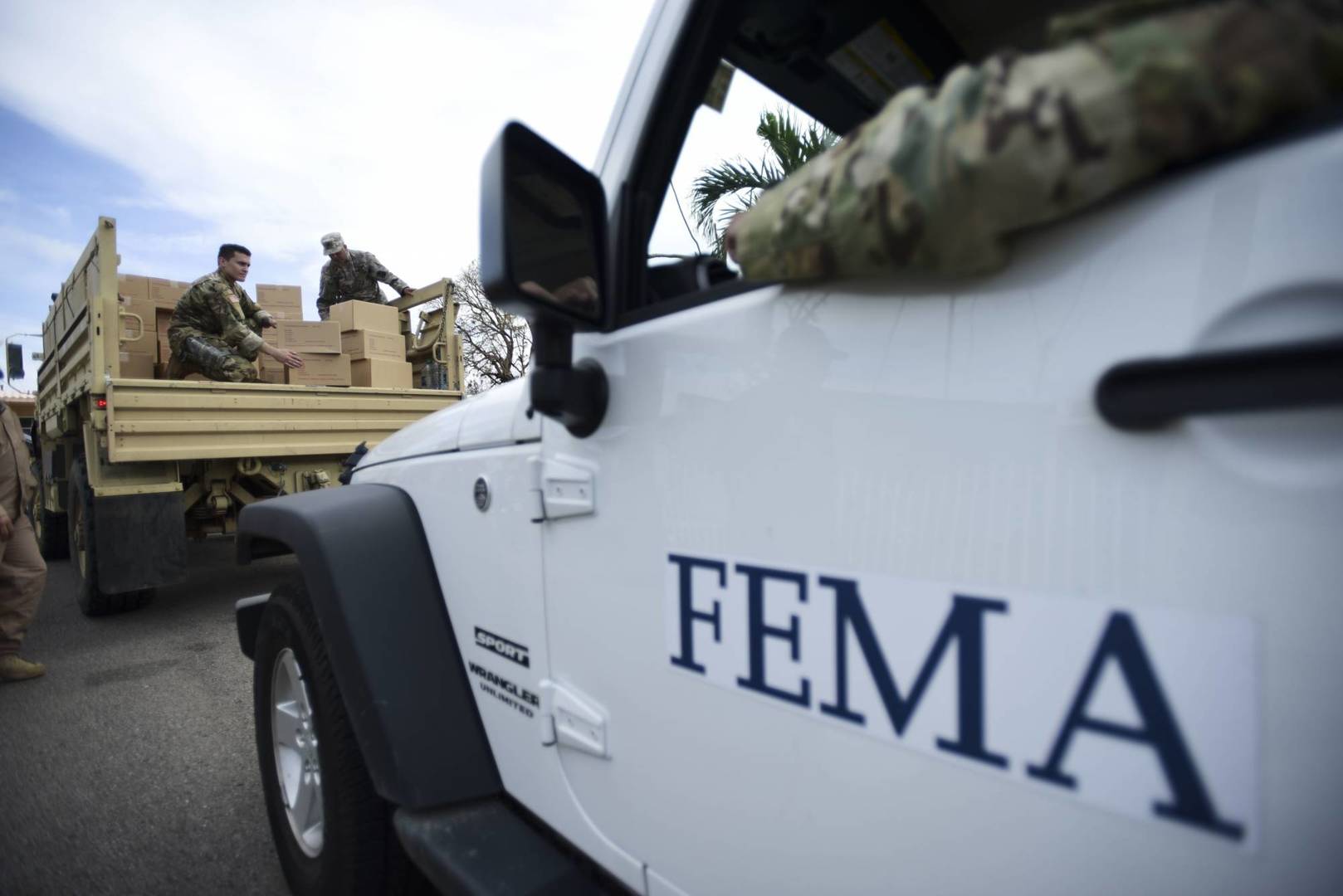 FILE - In this Oct. 5, 2017 file photo, Department of Homeland Security personnel deliver supplies to Santa Ana community residents in the aftermath of Hurricane Maria in Guayama, Puerto Rico. Federal authorities said Tuesday, Sept. 10, 2019, that they have arrested two former officials of the Federal Emergency Management Authority and the former president of a major disaster relief contractor, accusing them of bribery and fraud in the efforts to restore electricity to Puerto Rico in the wake of Hurricane Maria. (AP Photo/Carlos Giusti, File)