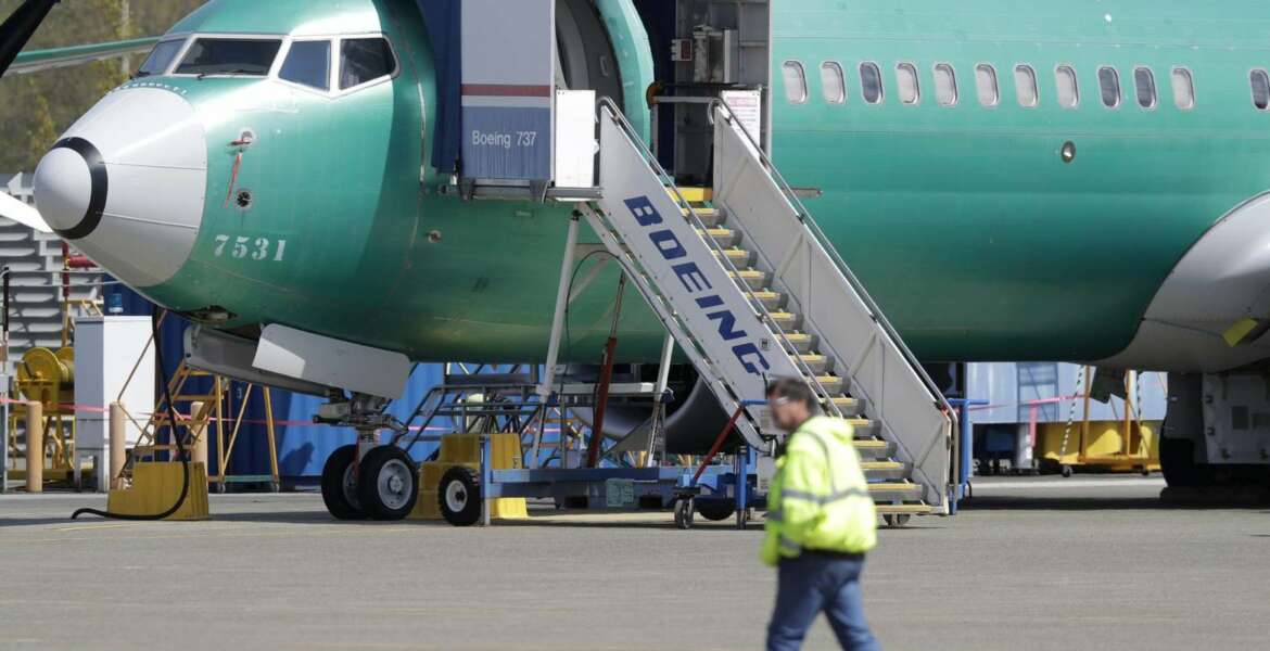 FILE - In this April 26, 2019, file photo a worker walks past a Boeing 737 MAX 8 airplane being built for Oman Air at Boeing's assembly facility in Renton, Wash. Passengers who refuse to fly on a Boeing Max won’t be entitled to compensation if they cancel. However, travel experts think airlines will be very flexible in rebooking passengers of giving them refunds if they’re afraid to fly on a plane that has crashed twice. (AP Photo/Ted S. Warren, File)