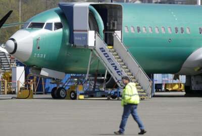 FILE - In this April 26, 2019, file photo a worker walks past a Boeing 737 MAX 8 airplane being built for Oman Air at Boeing's assembly facility in Renton, Wash. Passengers who refuse to fly on a Boeing Max won’t be entitled to compensation if they cancel. However, travel experts think airlines will be very flexible in rebooking passengers of giving them refunds if they’re afraid to fly on a plane that has crashed twice. (AP Photo/Ted S. Warren, File)