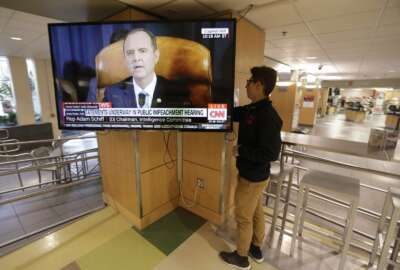 University of Utah student Suyog Shrestha turns on a TV in the student union on the campus in Salt Lake City as Rep. Adam Schiff, the Democratic chairman of the House Intelligence Committee, makes his opening remarks Wednesday, Nov. 13, 2019. The U.S. House launched the first public hearing Wednesday of Donald Trump's impeachment investigation, the extraordinary process to determine whether the 45th president of the United States should be removed from office. (AP Photo/Rick Bowmer)